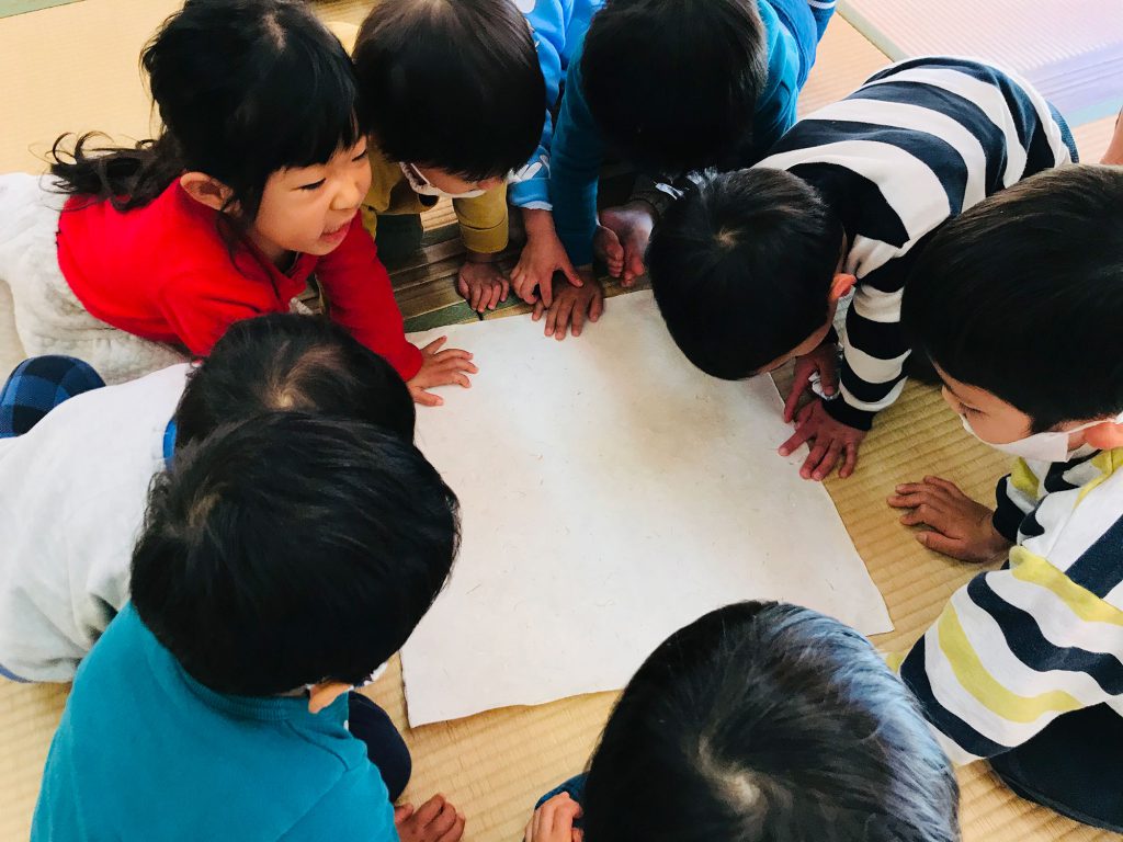 写真：和紙を囲む子供達の頭