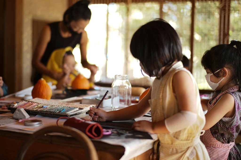写真：オレンジのかぼちゃや画材の並んだテーブルに向かう子どもたち