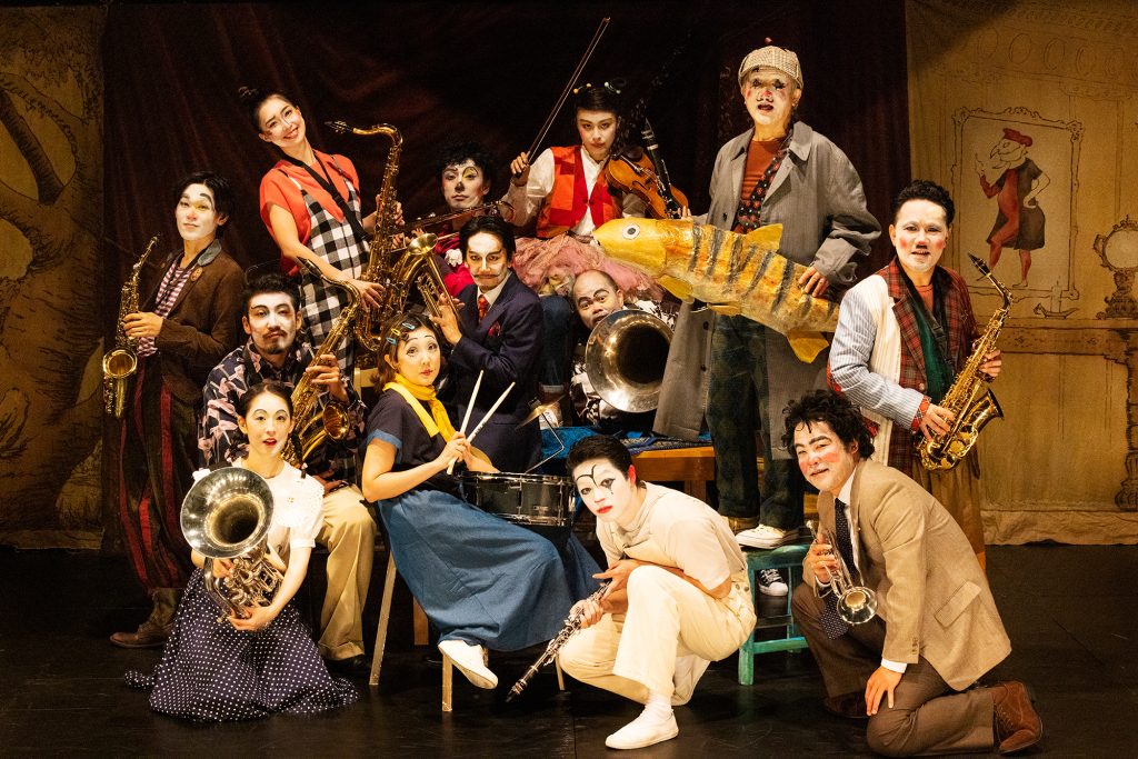 写真：出演者13名が舞台上でさまざまな楽器を抱えてポーズをとっている。