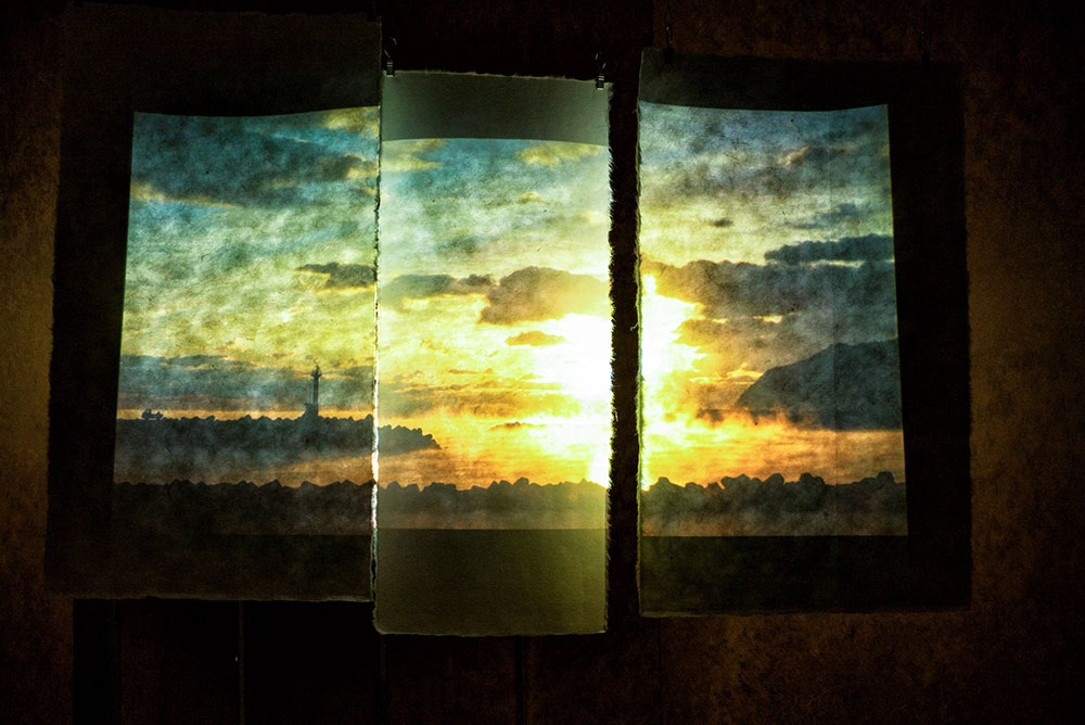 写真：3枚の和紙に投影された夕陽と海岸の風景