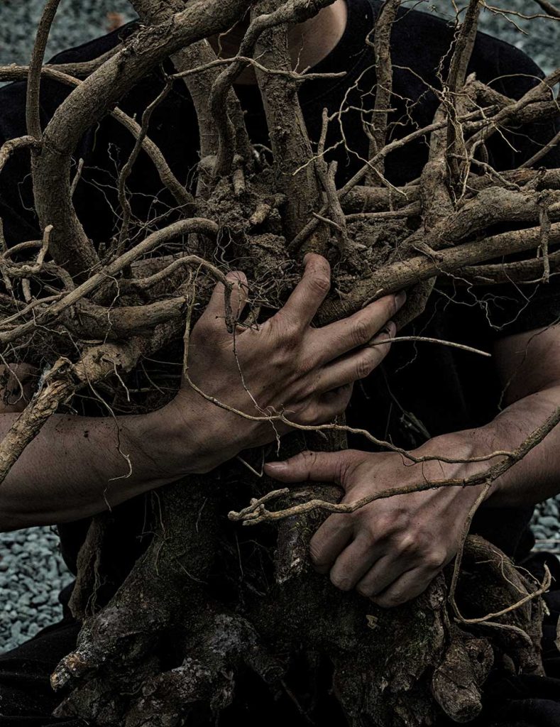写真：木の根っこを抱きかかえた人